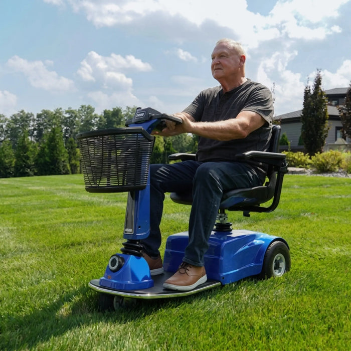 A man using the Amigo RD Scooter outside a short grassed ground