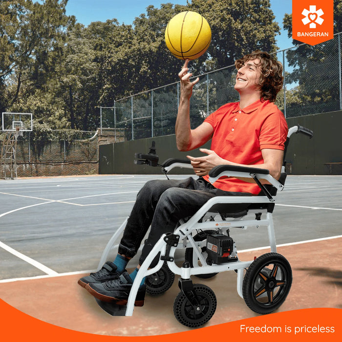 Person in a Bangeran Phoenix kids electric wheelchair balancing a basketball on their hand on a basketball court, with 'Bangeran' logo visible.
