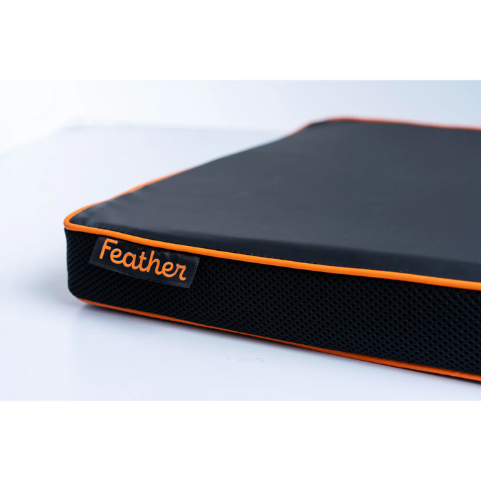 Black and orange feathe wheelchair cushion with 'Feather' branding on a white background
