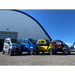 GIOEnclosedAllSeasonMobilityCar Four small electric vehicles in different colors parked in front of a building with a blue sky.