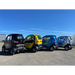 Four small GIO Enclosed All Season Mobility Scooter  electric cars in black, yellow, blue, and gray parked on a clear day.