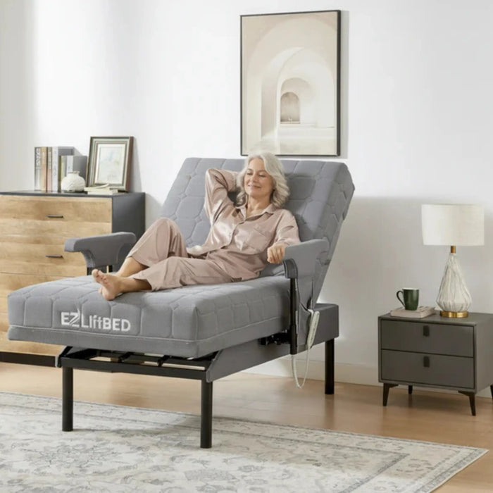 Senior woman relaxing in the EZLift Bed Deluxe Sleep To Stand Bed in Recliner Position, with the backrest elevated and leg section raised to provide comfortable support for resting and leisure activities.
