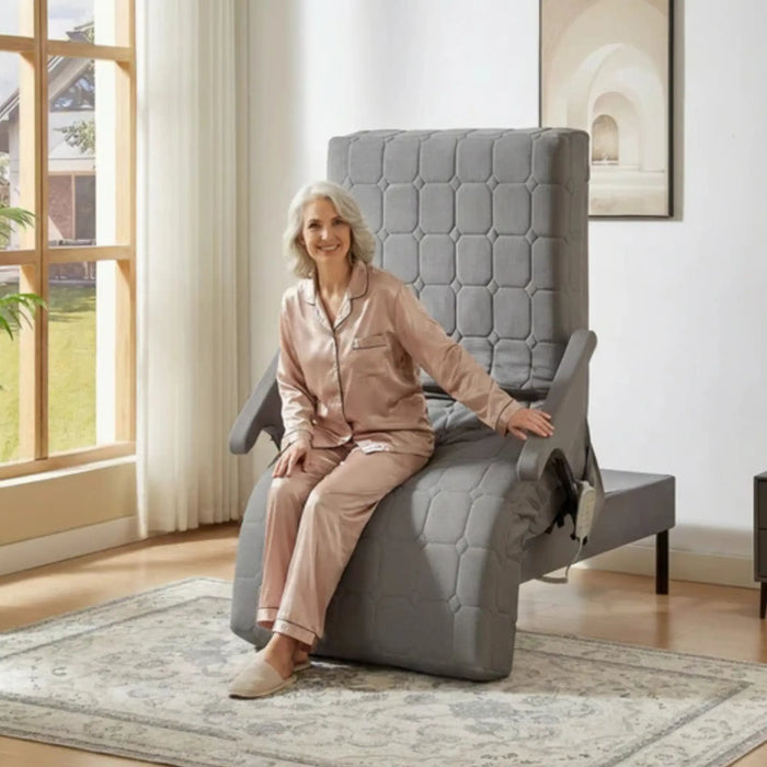 Senior woman seated at the front edge of the EZLift Bed Deluxe Sleep To Stand Bed in a transfer-ready position, designed to assist with safe entry, exit, and mobility transitions.
