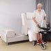 Older adult standing beside the EZLift Bed Elevra Rotating Adjustable Bed with a rollator walker after a safe assisted transfer from the bed.