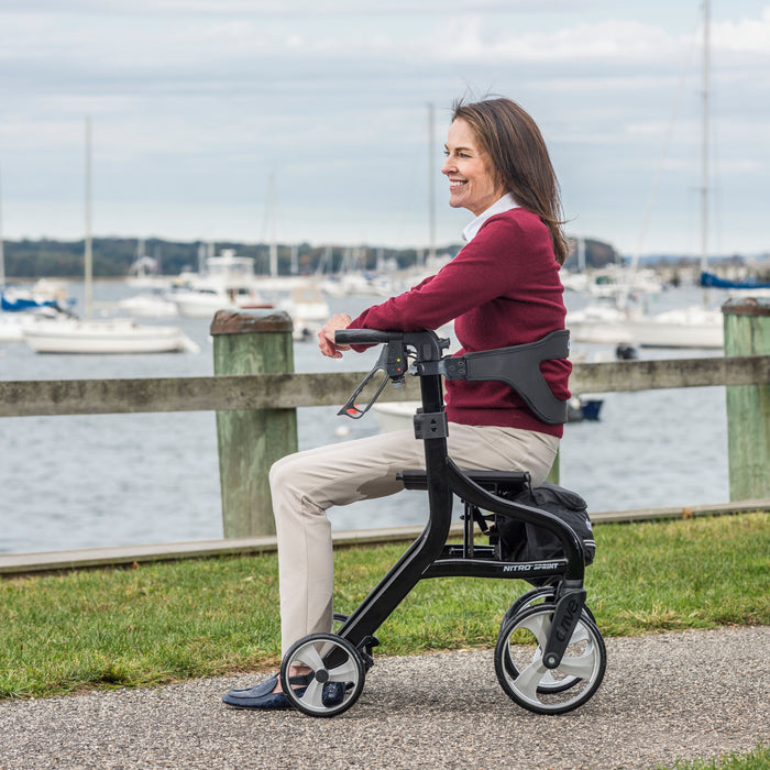 Nitro Sprint Rollator Rolling Walker, Black with a woman sitting on it
