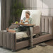 Woman seated comfortably in an adjustable bed using the StarSleep Motion Bed-Side Table for dining, with food and beverages placed securely on the tabletop for convenient bedside meals.