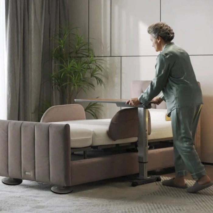 User moving the StarSleep Motion Bed-Side Table alongside an adjustable bed, demonstrating smooth mobility, easy positioning, and convenient access for everyday bedside activities.